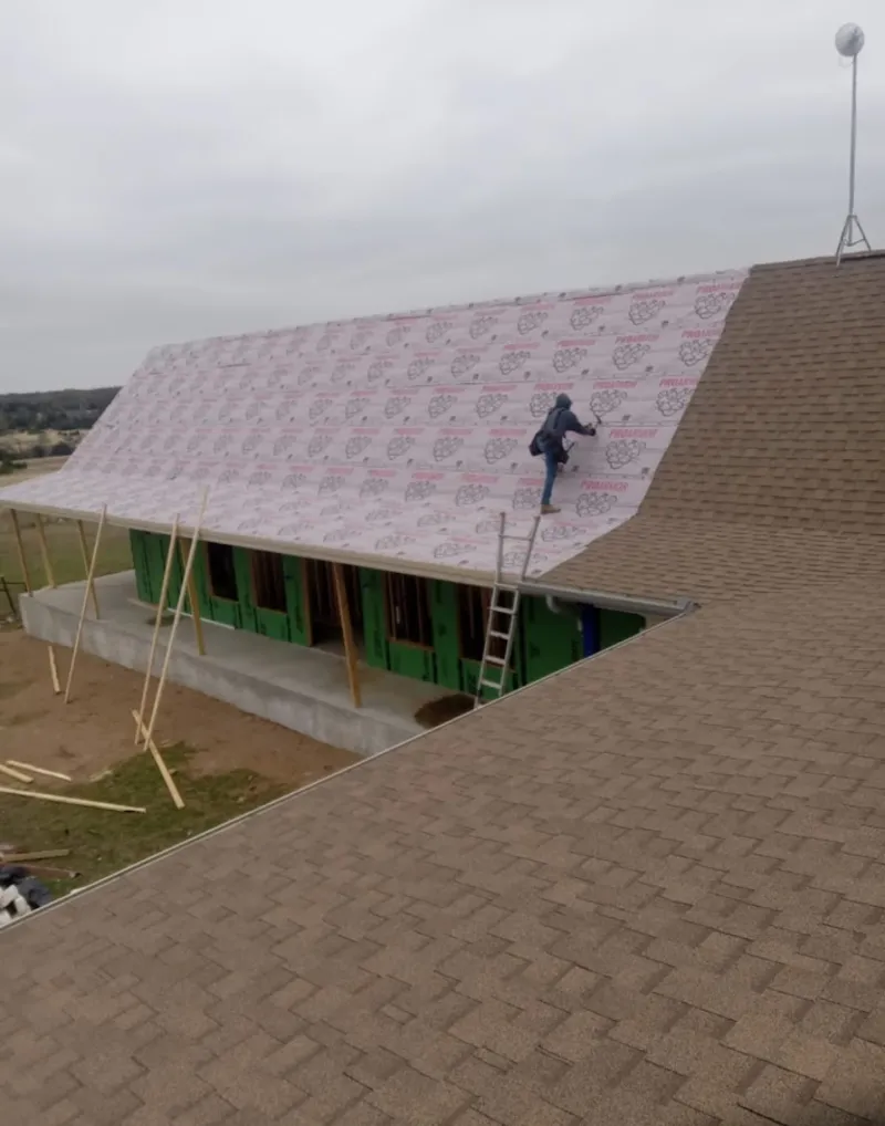 Worker preparing underlayment for a metal roof installation in Manistee
